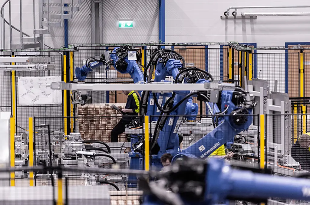 Bras robotiques palettisant des cartons dans une cellule d’automatisation sécurisée.